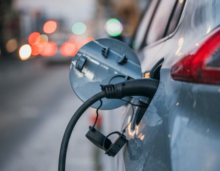 Close-up_of_an_electric_car_charging._Traffic_lights_in_a_blurry_background